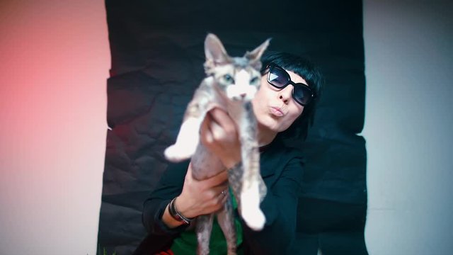 A blogger in black glasses holds a cat in his hands.