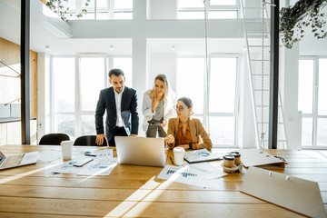 Group of a young office employees dressed casually in the suits having some office work at the...