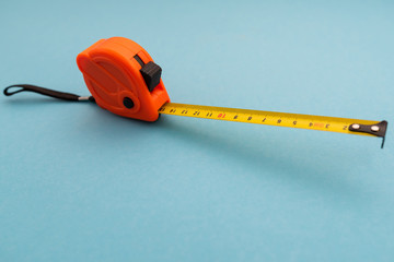 orange plastic construction tape measure on blue background
