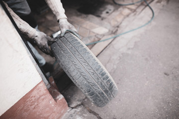 Shallow depth of field (selective focus) image with a mechanic changing the regular summer tyres of a car with winter tyres in a dirty car service..