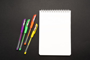 school white notebook with pen on black background