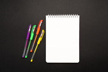 school white notebook with pen on black background