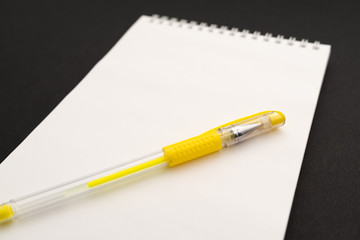 school white notebook with pen on black background