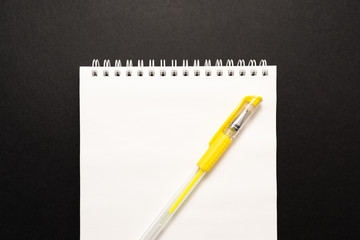 school white notebook with pen on black background