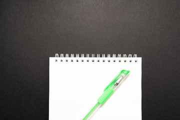school white notebook with pen on black background