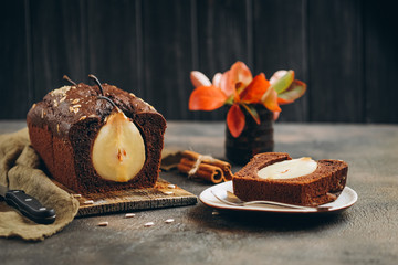 Homemade pastries. Chocolate cake with pear and cinnamon on a dark background copy space