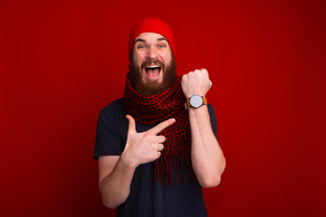 Photo of happy bearded guy, pointing at his newa watch, and delayed at meeting - obrazy, fototapety, plakaty