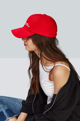 Cropped side photo of a girl, wearing red baseball cap with lettering 