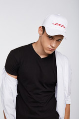 Cropped front view shot of a dark-haired man, wearing white baseball cap with lettering 