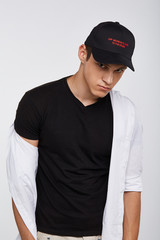 Cropped front view shot of a dark-haired man, wearing black baseball cap with lettering 