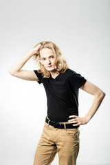 A young handsome guy with long blonde hair, isolated on a light background.