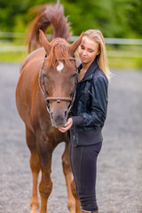 Fototapeta premium Young woman with her arabian horse standing at a riding course