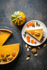 Traditional american homemade holiday pumpkin pie on a dark background with pumpkins top view copy space.