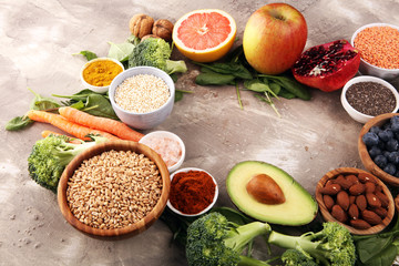 Healthy food clean eating selection: fruit, vegetable, seeds, superfood, cereals, leaf vegetable on rustic background