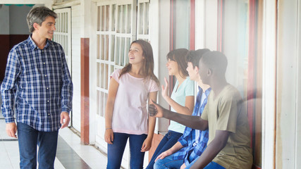 Teacher in the school hallway talking to his multi ethnic classroom