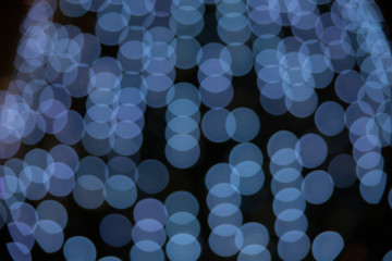 Texture of abstract blue bokeh from the lights of a Christmas tree on a dark background.