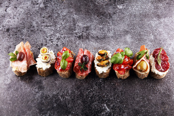 Appetizers table with italian antipasti snacks and wine in glasses. Brushetta or authentic traditional spanish tapas set, cheese variety