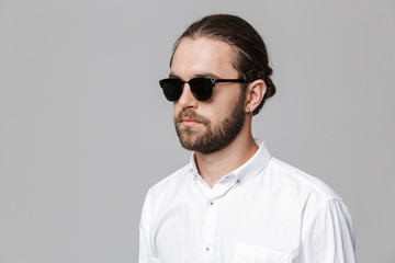 Man posing isolated over grey wall background wearing sunglasses.