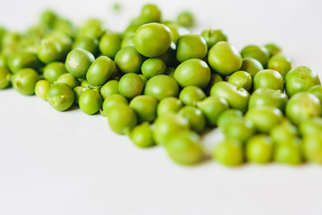 On a white background scattered with fresh green peas, there is a place for an inscription.