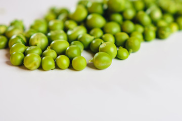 On a white background scattered with fresh green peas, there is a place for an inscription.