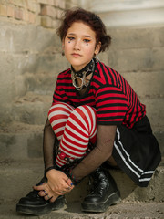 Goth emo girl portrait with a skirt, striped stockings and heels boots sitting on the steps - obrazy, fototapety, plakaty