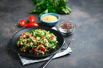 Traditional oriental salad Tabbouleh with bulgur and parsley on a dark background copy space.