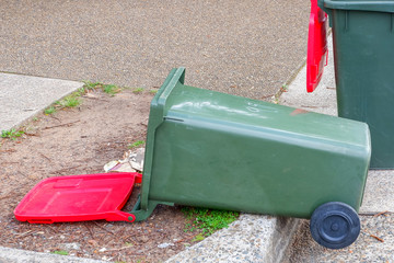 Australian garbage wheelie bins red lids for general waster stay and lie down on the street kerbside after council rubbish collection