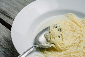 European tasty noodle soup in a white plate, close up shot