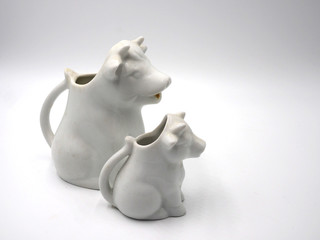 Dos jarras lecheras con forma de vaca sentada.