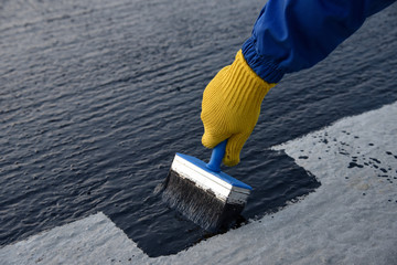 Worker applies bitumen mastic on the foundation