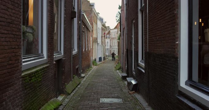 A small alleyway in Middelburg, with a man walking next to his bicycle.