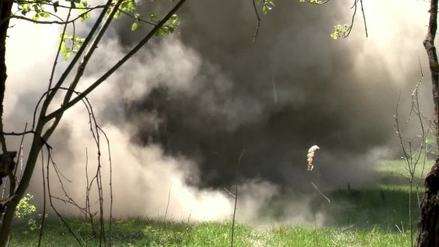 Moscow, Russia - May 09, 2013: People in uniform on background of military hand grenade explosion in forest. Impact strength and power of airsoft guns.