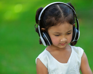 asian girls listen to music from the headphone happily green background