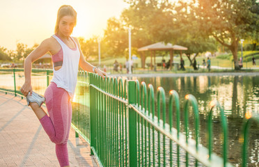 Young fitness woman stretching outdoors at sunset