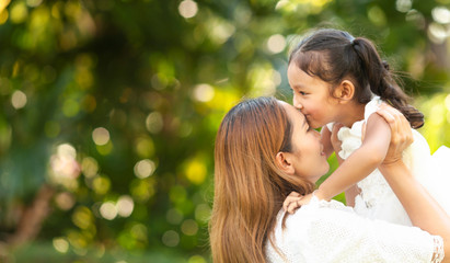 Happy family on a summer meadow. little girl child baby daughter hugging and kissing mother