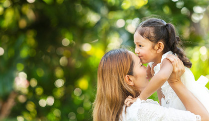 mom kissing preschooler girl. mother and daughter sitting together. lifestyle concept with young mom and child