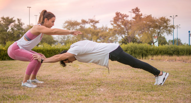 Handstand training. Athletic man doing a balancing handstand exercise together with female yoga partner