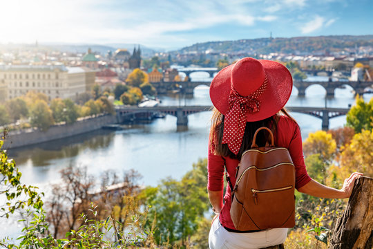 Touristin mit Hut genie&szlig;t die Aussicht auf die Karlsbr&uuml;cke und die Altstadt von Prag, Tschechiche Republik, an einem sonnigen Herbsttag
