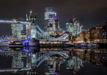 Die beleuchtete City von London und Skyline der Stadt bei Nacht mit Reflektionen im Fluss Themse,...