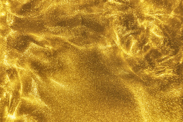 Abstract elegant, detailed gold glitter particles flow with shallow depth of field underwater....