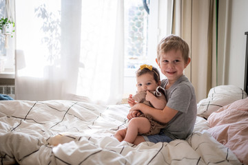 little infant baby girl sitting together with her toddler brother