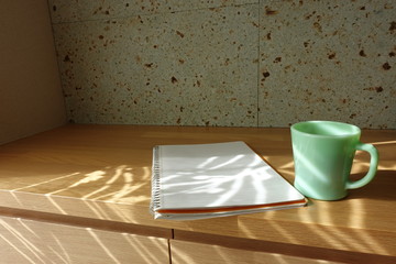 木製テーブルに置かれたコーヒーカップとノート　cup of coffee and book on wooden table