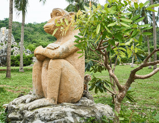 Obraz premium Macaque monkey hide behind monkey statue. Monkey Island, Vietnam, Nha Trang