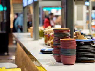 Deep dishes stacked in piles on a kitchen counter in a fast food restaurant. Cooks on a blurred background. Cooking process.