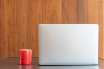 workstation using a laptop and holding a cup of coffee with wood background