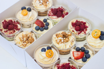 Box of assorted cupcakes with cream cheese vanilla and chocolate frosting, fresh strawberries, raspberries, blueberries and popcorn decoration. 