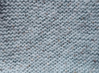 Photo background with soft knitted fabric decorated with tiny golden sequins. Light blue knitted textile texture.