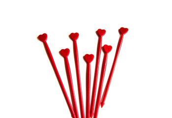 Red plastic sticks for canapes with a heart on a white isolated background. Copy space.