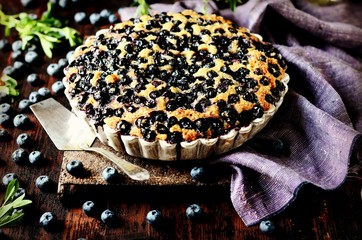 Cake with blueberries on a dark wooden background, still life