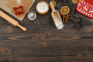 Christmas food background for baking gingerbread cookies with cutters, rolling pin, dough, flour and spices ondark wood table. Copy space for christmas recip